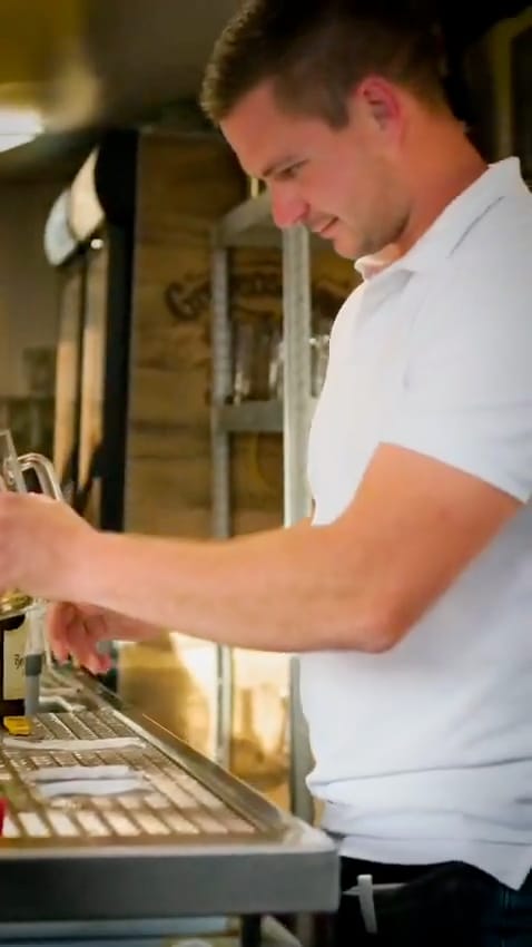 Mitarbeiter zapft ein Bier an der Theke